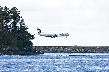 An Alaska Air commercial jet preparing to land at Sitka International Airport just outside the town of Sitka, southeast Alaska, USA.