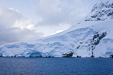 The Lindblad Expedition ship National Geographic Explorer transits Lemaire Channel in late evening light on the west side of the Antarctic peninsula in Antarctica