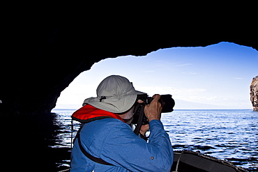 Lindblad Expeditions Guest taking photos inside sea grotto in the Galapagos Island Archipeligo, Ecuador. No model or property release are available for this image.