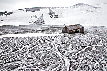 Snow covering the ash and mud slides at Whalers Bay inside of the caldera at Deception Island, South Shetland Islands, Antarctica, Southern Ocean