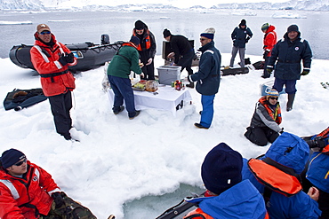 Guests from the Lindblad Expedition ship National Geographic Explorer enjoy a hot asado sandwich prepared by staff at BBQ on an ice floe near Adelaide Island, Antarctica