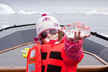 Guest Poppy (6) from the Lindblad Expedition ship National Geographic Explorer examines glacial ice near Petermann Island, Antarctica