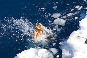 Guests from the Lindblad Expedition ship National Geographic Explorer take the Polar Plunge off ice floe in the Weddell Sea, Antarctica, Southern Ocean