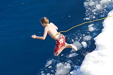 Guests from the Lindblad Expedition ship National Geographic Explorer take the Polar Plunge off ice floe in the Weddell Sea, Antarctica, Southern Ocean