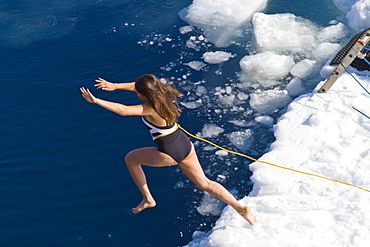 Guests from the Lindblad Expedition ship National Geographic Explorer take the Polar Plunge off ice floe in the Weddell Sea, Antarctica, Southern Ocean