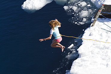 Guests from the Lindblad Expedition ship National Geographic Explorer take the Polar Plunge off ice floe in the Weddell Sea, Antarctica, Southern Ocean