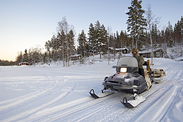 Man on a snowmobile driving over frozen lake, Sweden