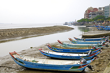 Sampan style fishing boats moored on the shoreline of the Tamsui River estuary at low tide, Tamsui (Danshui), Taiwan, Asia