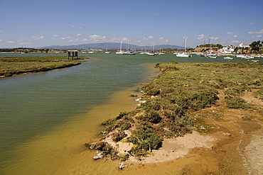 Saltmarsh, estuarine harbour at high tide and moored sailing yachts, Alvor, near Portimao, Algarve, Portugal, Europe