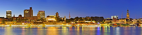 Panorama of Hamburg with view over the river Elbe to illuminated St. Pauli-Landungsbruecken with skyscrapers, Pegelturm, Heinric