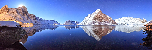 Panoramic view of snowy peaks reflected in the frozen sea on a starry night, Reine Bay, Nordland, Lofoten Islands, Arctic, Norway, Scandinavia, Europe