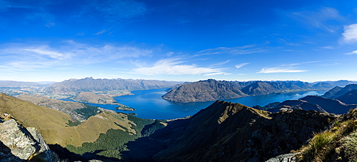 Steep sharp mountains, a deep blue lake, and mountain town in Queenstown, Otago, South Island, New Zealand, Pacific