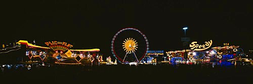 Ferris wheel and neon signs lit up at night in an amusement park, Oktoberfest, Munich, Germany