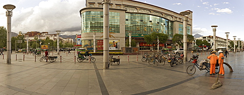 Panorama showing the Potala Palace in the distance and a department store on a modern high street, Lhasa, Tibet, China, Asia