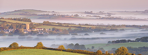 Rural Dartmoor village and church tower surrounded by mist covered countryside at dawn, South Tawton, Devon, England, United Kingdom, Europe