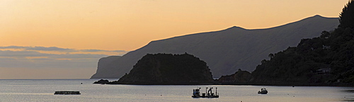 Sun rising over Akaroa Harbor at Banks Peninsula, seen from Wainui, New Zealand