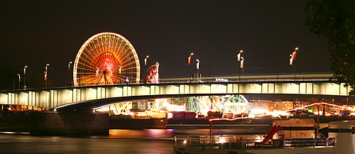 Panorama across Deutzer bridge over the Rhine river and fair lights with the big wheel in Cologne, NRW, Germany