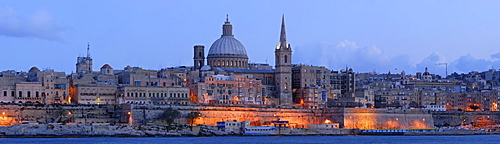 The skyline of Valletta dominated by the floodlit cupola of the Carmelite Church and the tower of St. Paul's Cathedral at the blue hour just after sunset, as seen from Sliema, Malta, Europe