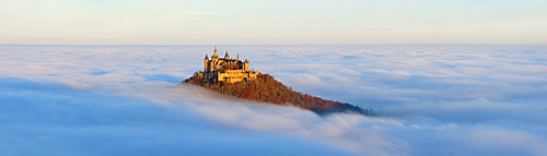 Burg Hohenzollern castle in morning light, mist, with autumn forest, Schwaebische Alb, Swabian Alb, Baden-Wuerttemberg, Germany, Europe