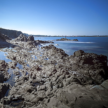 Rocky beach at low tide with man fishing on rock, Argelles, France, Europe