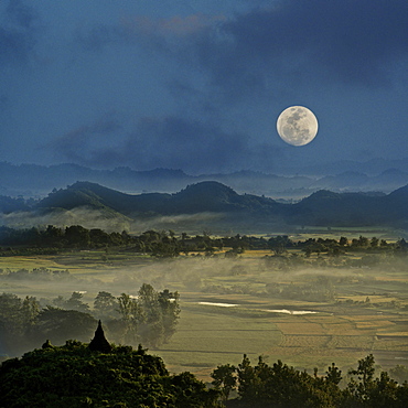 Full moon in Burma, view above hill and pagoda in the morning mist at Mrauk U, Myohaung north of Sittwe, Akyab, Rakhaing State, Arakan, Myanmar, Burma