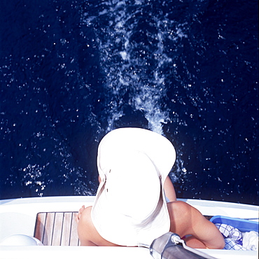 Woman sitting at back of sailboat and cooling her feet in Adriatic Sea, Dalmatia, Croatia