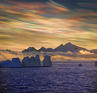 Mother of pearl clouds, nacreous clouds over snow covered iceberg, Antarctic Peninsula, Antarctica