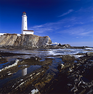 Lighthouse by a rocky shore, Cap-des-Rosiers, Gaspe Coast, Quebec