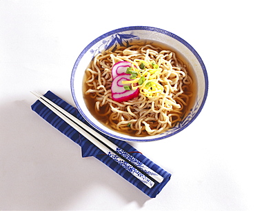 Studio shot of a bowl of Japanese Ramen with chopsticks on a napkin next to it.