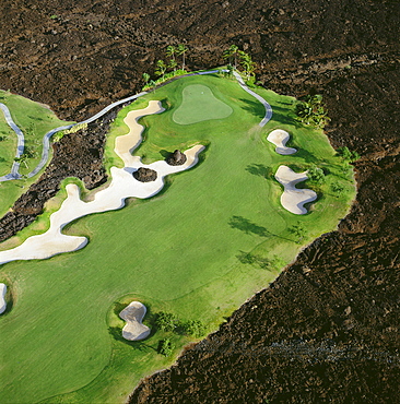 Hawaii, Big Island, Aerial view of Waikoloa Resort hole #5 surrounded by lava field 