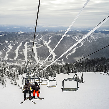 Skiers on a chairlift at Sun Peaks ski resort, Kamloops, British Columbia, Canada