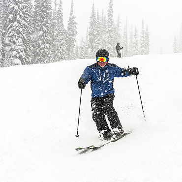 Skier going downhill in a heavy snowfall at Sun Peaks Resort, Kamloops, British Columbia, Canada