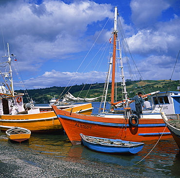 Fishermen on fishing boats moored on the beach at Dalcahue village on Chiloe Island, Chile, South America