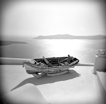 Image taken with a Holga medium format 120 film toy camera of old wooden boat on roof garden with Aegean Sea in background, Firostephani, Santorini, Cyclades, Greek Islands, Greece, Europe