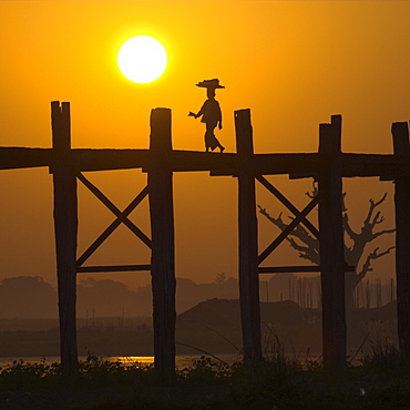 Woman on U Bein bridge on Taungthaman lake silhouetted against the sunset, Mandalay area, Myanmar (Burma), Asia