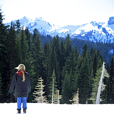 Blonde girl looks at snow covered peaks from the Paradise Lodge, Mount Rainier, Washington State, United States of America (U.S.A.), North America