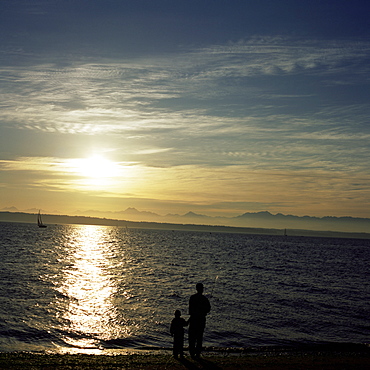 Father and son fish from Golden Gardens Park, Olympic Mountains in distance, Seattle, Washington State, United States of America (U.S.A.), North America