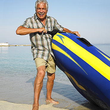 Senior man on beach with inflatable dinghy