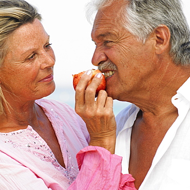 senior couple on beach holding apple