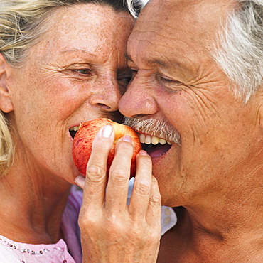 senior couple on beach holding apple