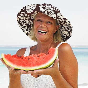 senior woman on beach holding water melon