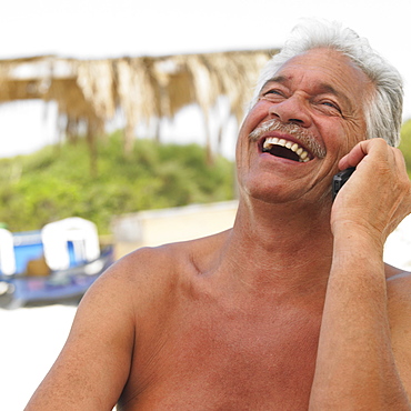 Senior man laughing on mobile phone, outdoors