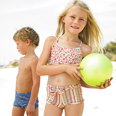 Boy and girl (6-8) on beach playing with ball