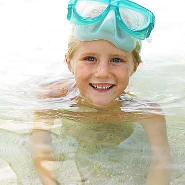 Girl (6-8) wearing swimming mask in the surf