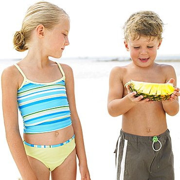 Boy and girl (6-8) on beach, boy holding