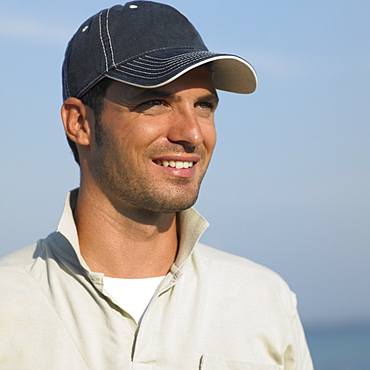 Man on beach wearing baseball cap