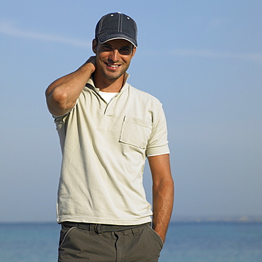 Man on beach wearing baseball cap