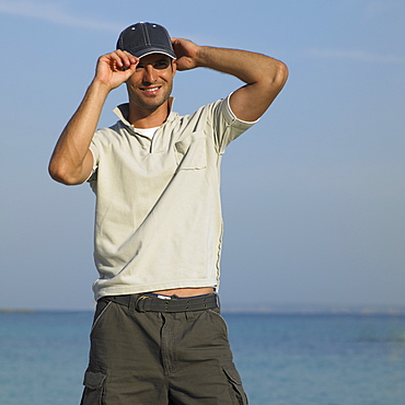 Man on beach wearing baseball cap