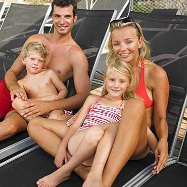 Family relaxing on sunloungers, children (6-8)
