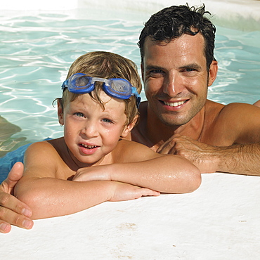 Father and son (6-8) in swimming pool